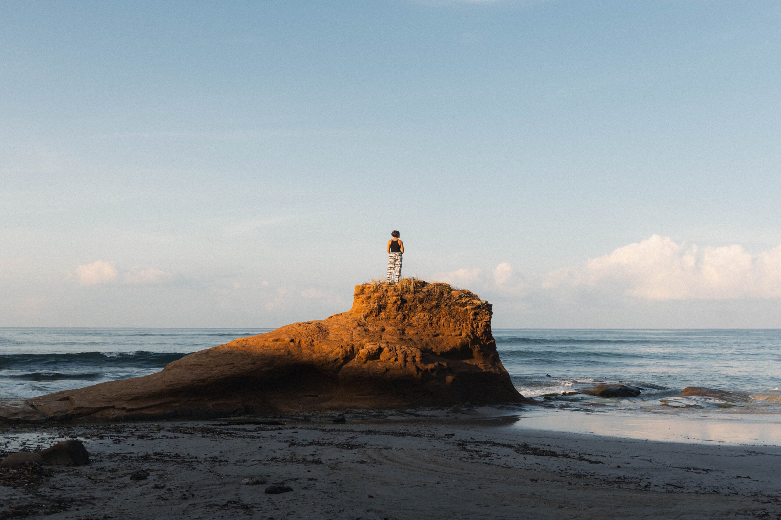A guest standing alone on a sea rock in the morning light